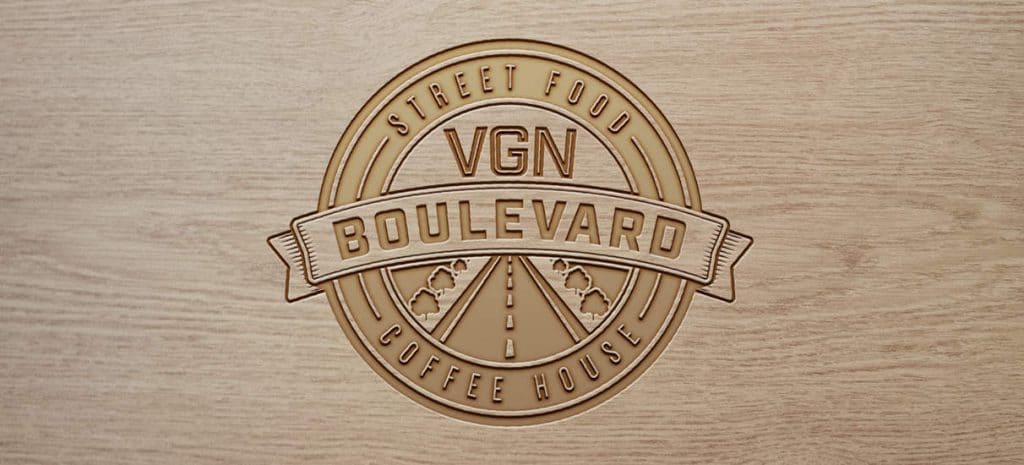 A creative logo for a vegan food brand, embossed on wood.