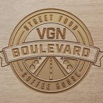 A creative logo for a vegan food brand, embossed on wood.
