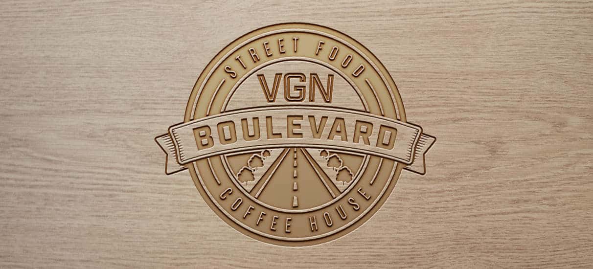 A creative logo for a vegan food brand, embossed on wood.
