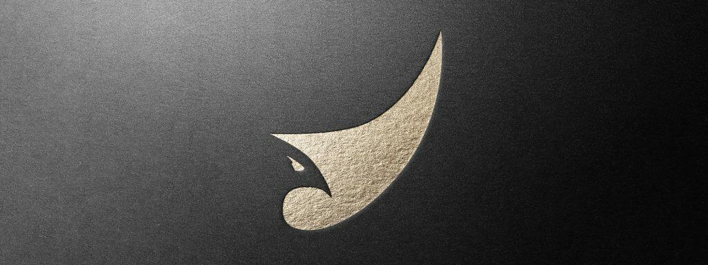 The minimalist Bird Wing logo shown with a gold foil effect on dark textured paper.